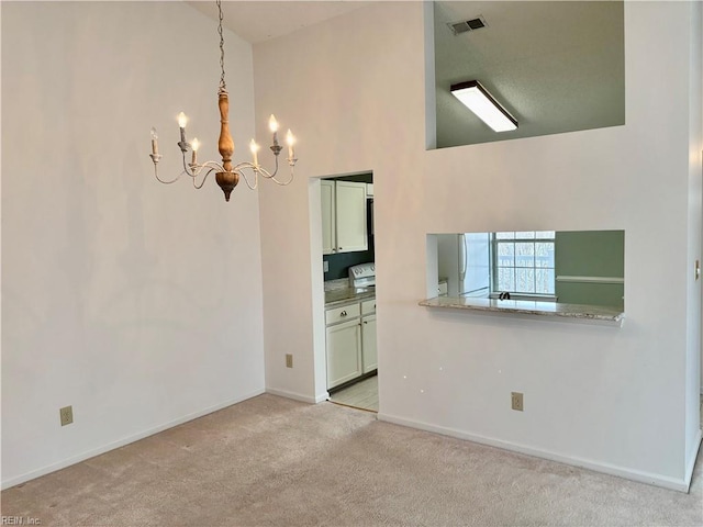 spare room with visible vents, baseboards, a chandelier, light colored carpet, and high vaulted ceiling