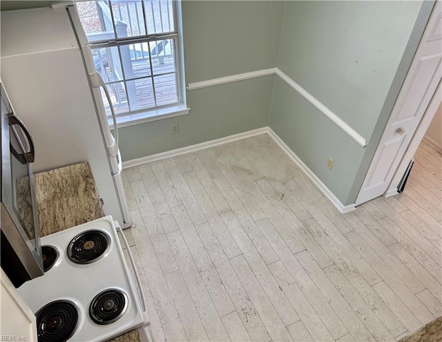 interior space featuring baseboards, wood finished floors, and freestanding refrigerator