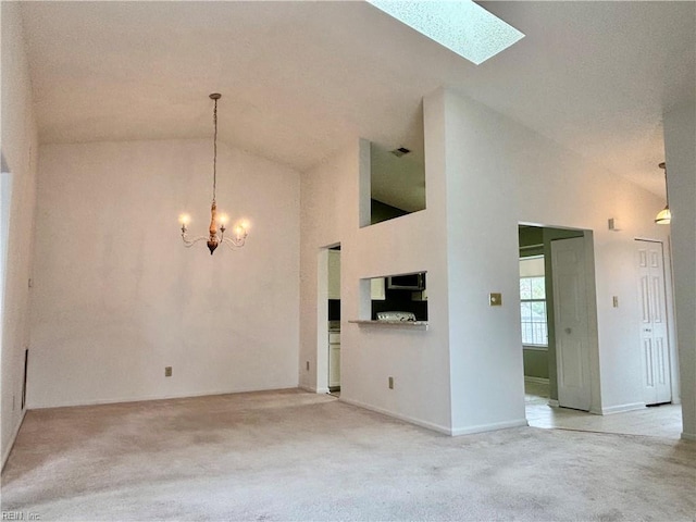 unfurnished living room featuring a skylight, light colored carpet, high vaulted ceiling, and a chandelier