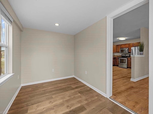 empty room featuring recessed lighting, baseboards, and light wood finished floors