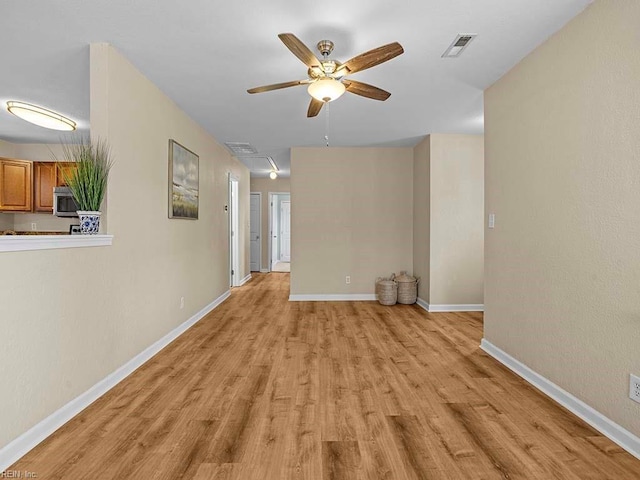 interior space with light wood finished floors, visible vents, baseboards, ceiling fan, and attic access