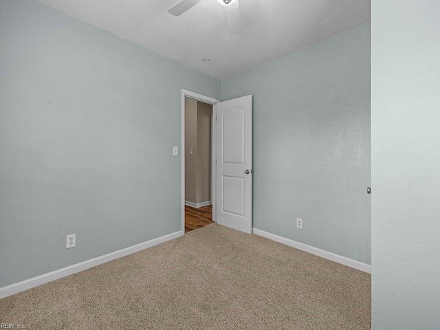 carpeted spare room featuring a ceiling fan and baseboards