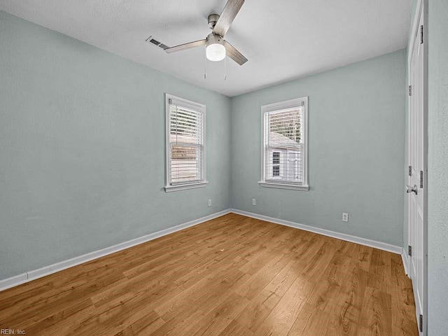 empty room with visible vents, a ceiling fan, light wood-type flooring, and baseboards