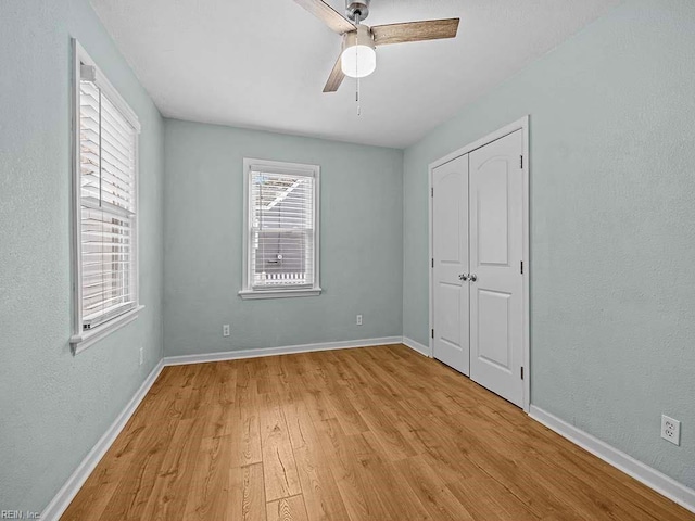 unfurnished bedroom with baseboards, ceiling fan, light wood-style flooring, a textured wall, and a closet