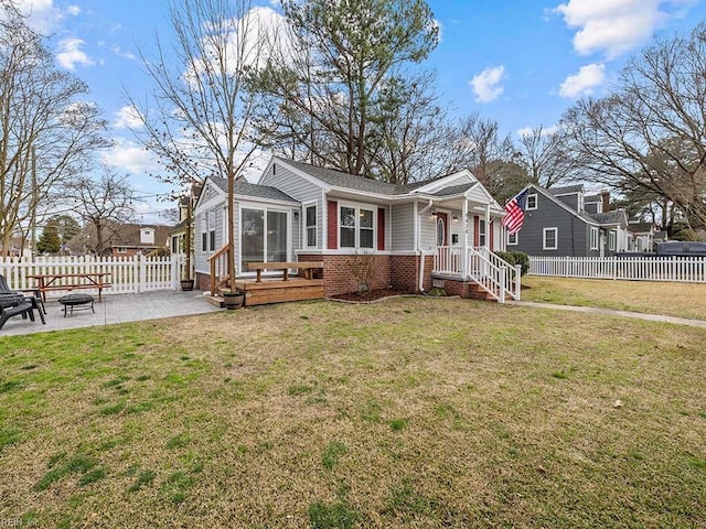 view of front of property featuring brick siding, a front lawn, an outdoor fire pit, fence private yard, and a patio area