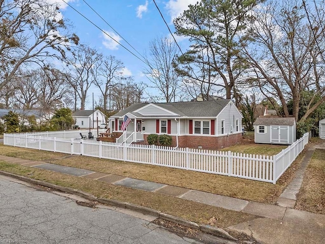 ranch-style house with a fenced front yard, a storage unit, an outbuilding, and brick siding