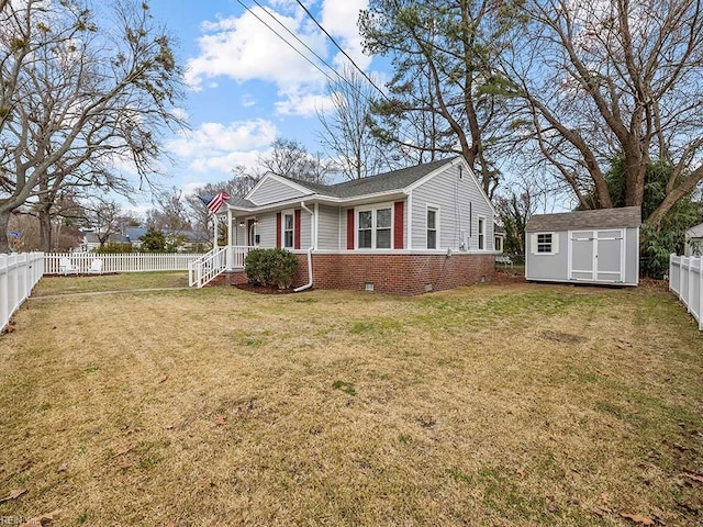 view of front of house featuring a front lawn, a fenced backyard, a storage shed, an outdoor structure, and brick siding