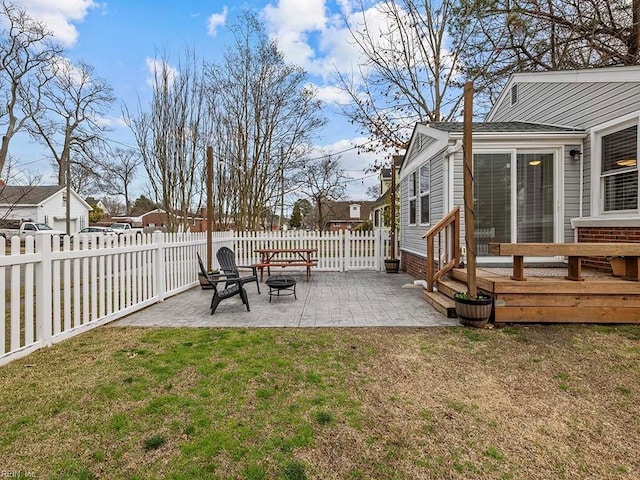 view of yard with a wooden deck, a patio, a fire pit, and a fenced backyard