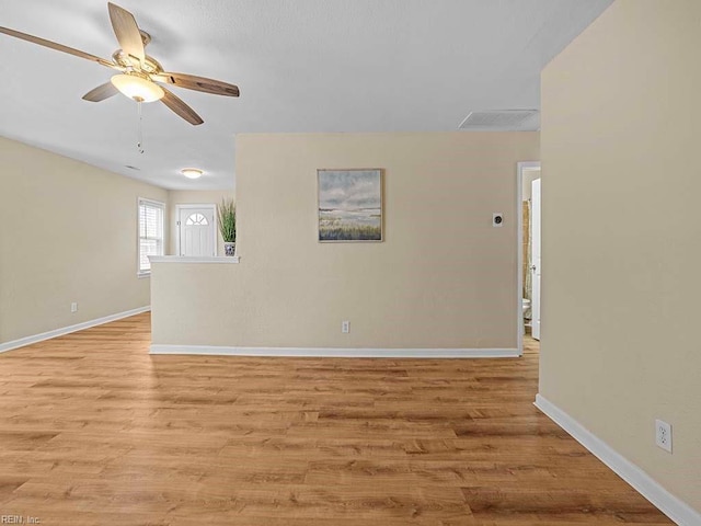 spare room featuring light wood-type flooring, baseboards, and a ceiling fan