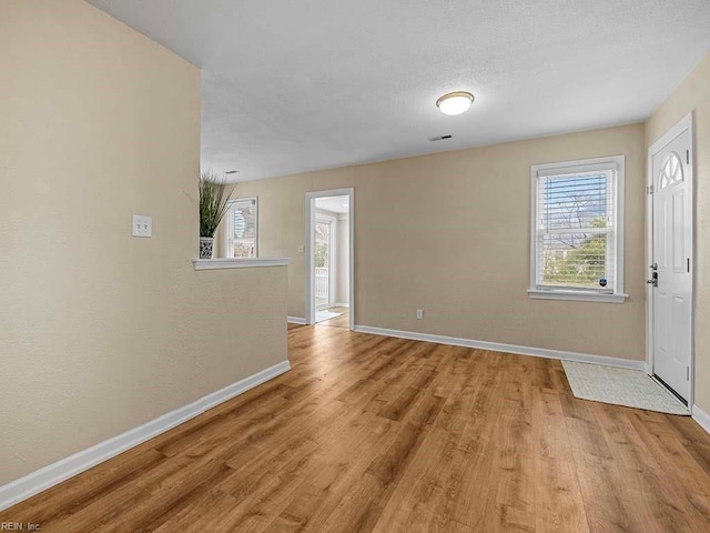 entryway featuring light wood-type flooring, baseboards, a textured ceiling, and visible vents