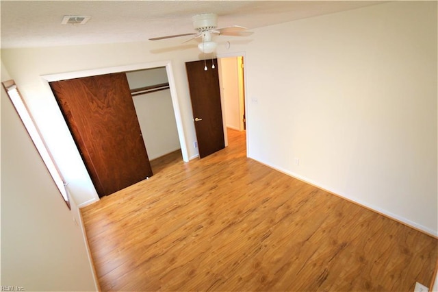 unfurnished bedroom featuring a closet, visible vents, light wood finished floors, and ceiling fan