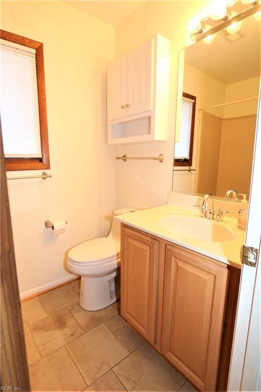 bathroom with toilet, vanity, and baseboards