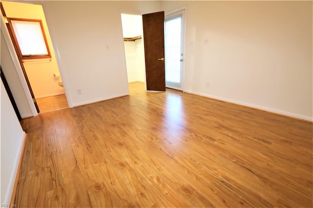 spare room featuring a wealth of natural light, baseboards, and wood finished floors