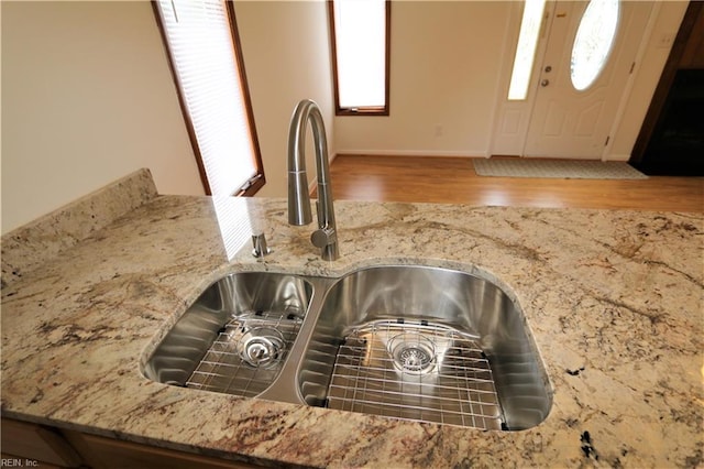 room details with wood finished floors, stone counters, and a sink