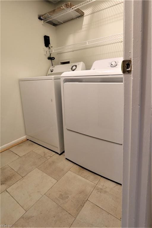 washroom featuring washing machine and clothes dryer, laundry area, baseboards, and light tile patterned floors