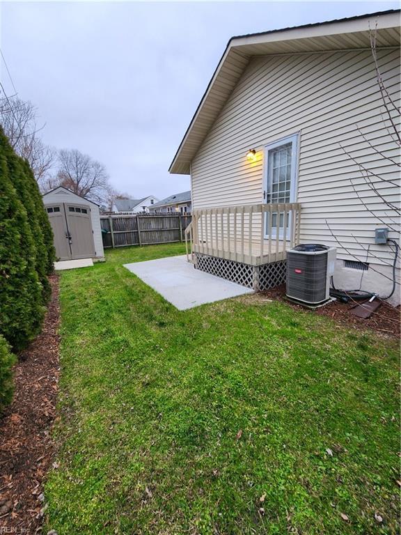 view of yard featuring central air condition unit, a patio, fence, a storage shed, and an outdoor structure