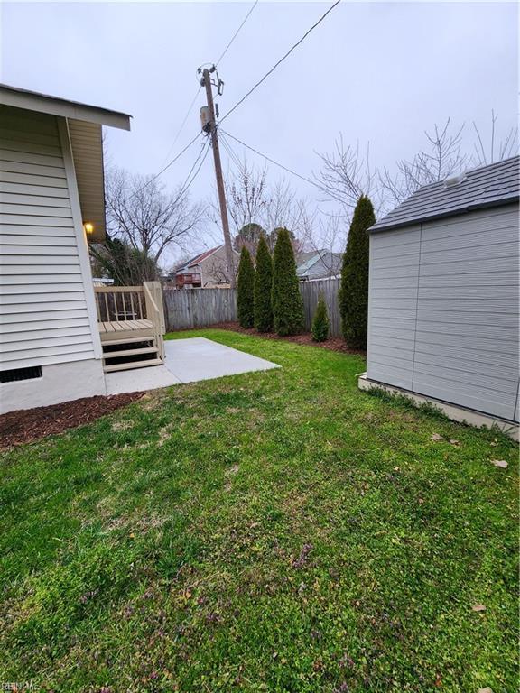 view of yard with a patio, an outbuilding, a shed, and fence