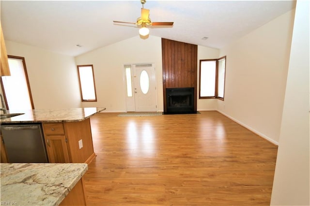 interior space with baseboards, light wood-style flooring, a fireplace, ceiling fan, and vaulted ceiling