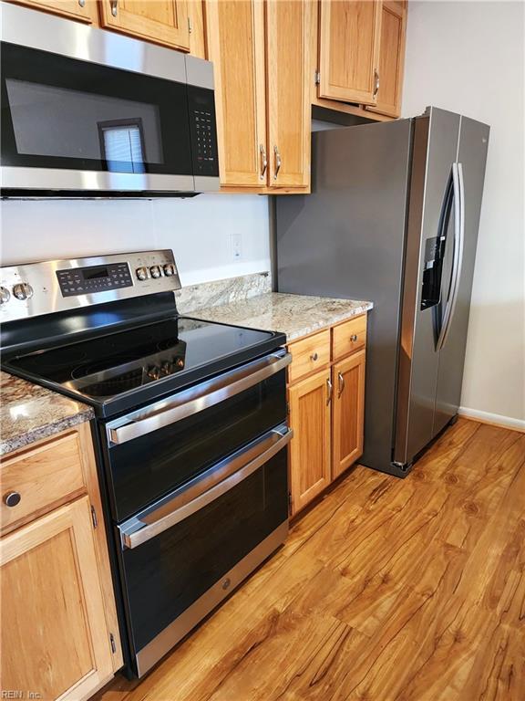 kitchen with appliances with stainless steel finishes, light countertops, and light wood finished floors