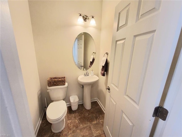 bathroom with toilet, baseboards, and a sink