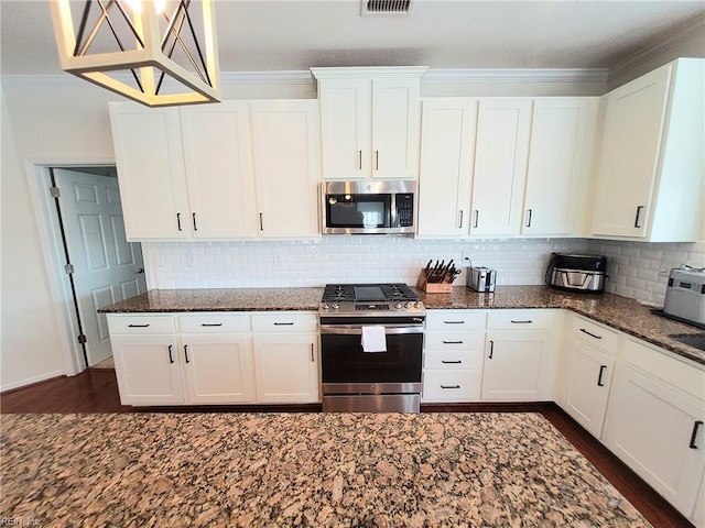 kitchen featuring white cabinetry, dark stone counters, appliances with stainless steel finishes, and decorative backsplash