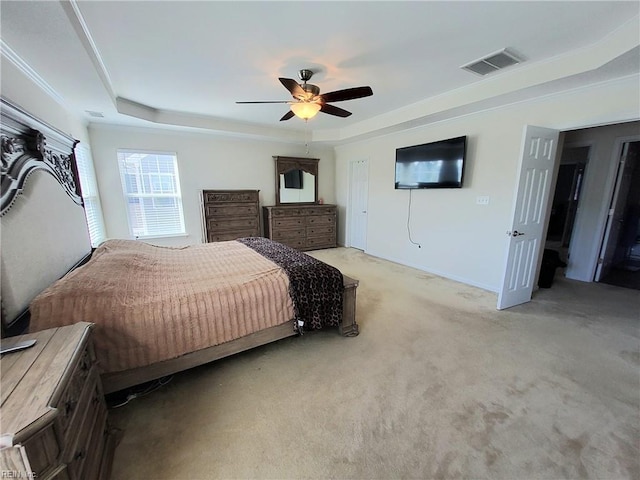 bedroom featuring a tray ceiling, light colored carpet, visible vents, and ceiling fan