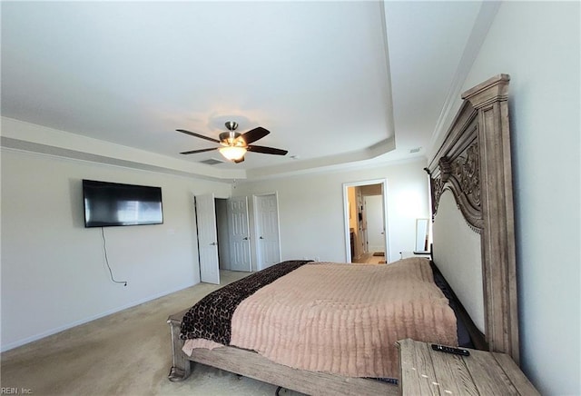 bedroom with visible vents, baseboards, a tray ceiling, ceiling fan, and light colored carpet