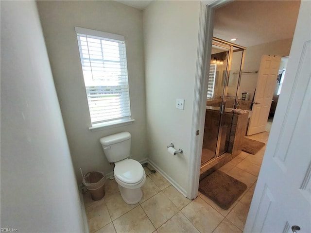 bathroom featuring tile patterned flooring, a shower stall, toilet, and baseboards