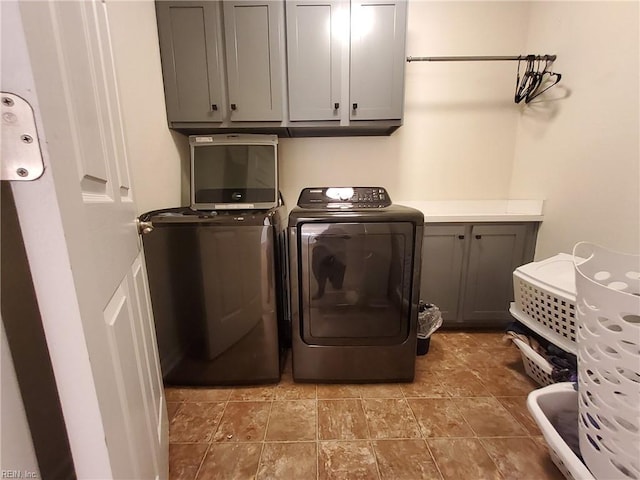 clothes washing area featuring washing machine and dryer and cabinet space