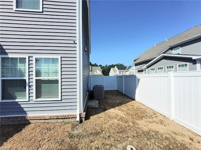 view of side of home with central air condition unit and a fenced backyard