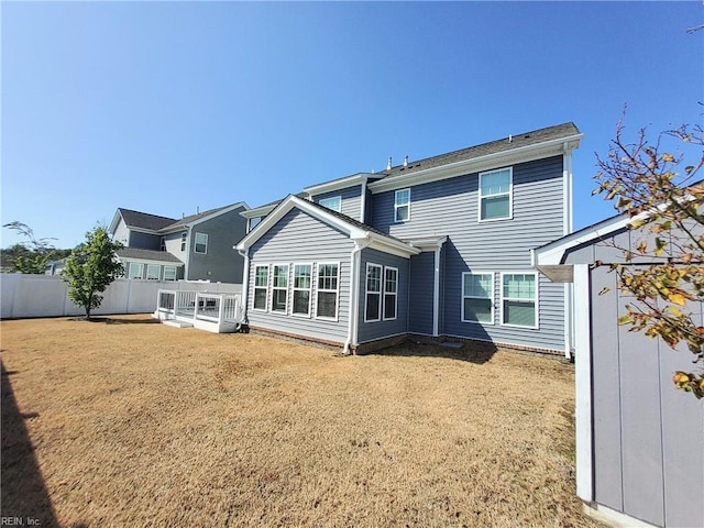 rear view of property featuring a yard and fence