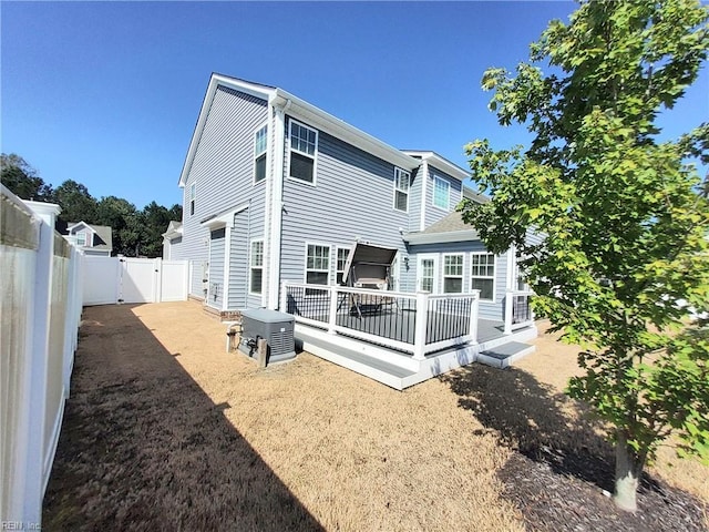 rear view of property with a wooden deck, a fenced backyard, and a gate