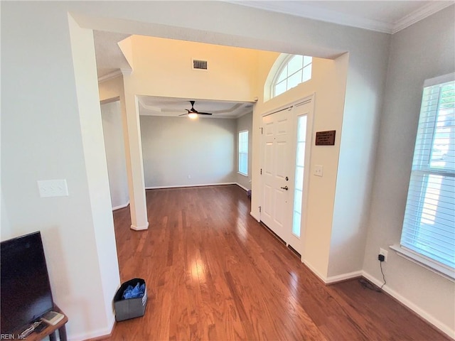 entrance foyer with visible vents, ornamental molding, a ceiling fan, wood finished floors, and baseboards