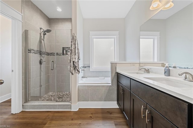 bathroom with a sink, wood finished floors, a garden tub, and a stall shower