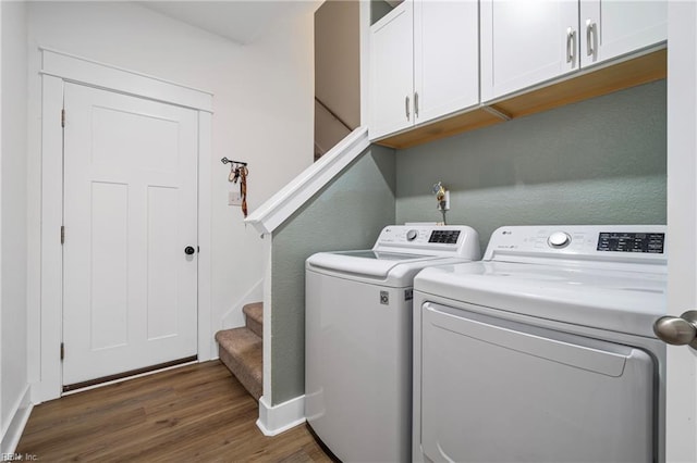 laundry room featuring washing machine and clothes dryer, cabinet space, dark wood finished floors, and baseboards