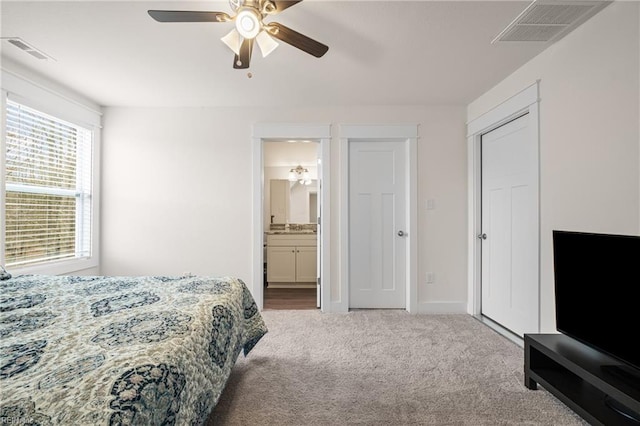 bedroom with visible vents, a ceiling fan, ensuite bathroom, and carpet