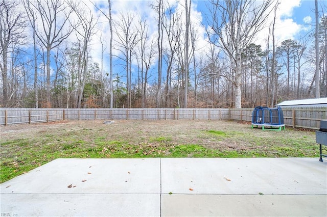 view of yard with a patio area, a fenced backyard, and a trampoline