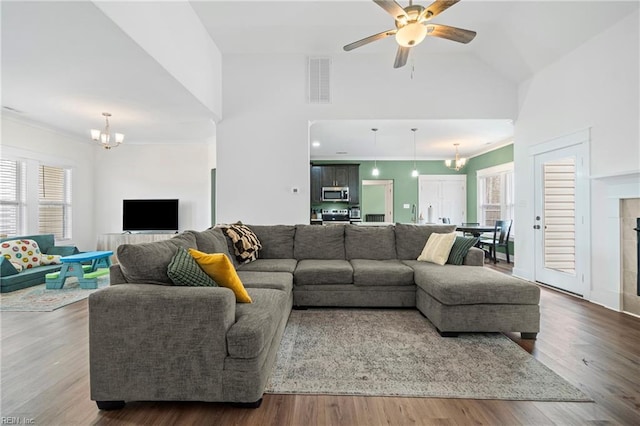 living area with plenty of natural light, ceiling fan with notable chandelier, visible vents, and wood finished floors