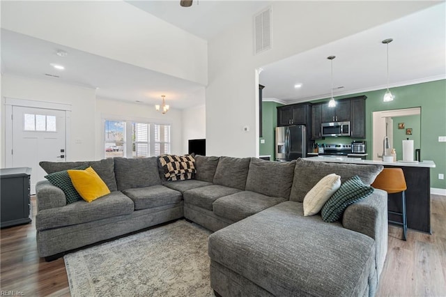 living room featuring visible vents, ornamental molding, recessed lighting, light wood-style floors, and baseboards