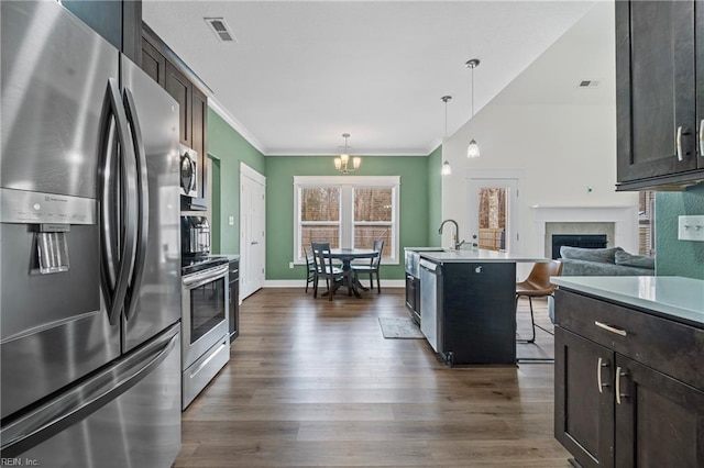 kitchen with visible vents, dark wood-type flooring, a kitchen bar, appliances with stainless steel finishes, and a fireplace