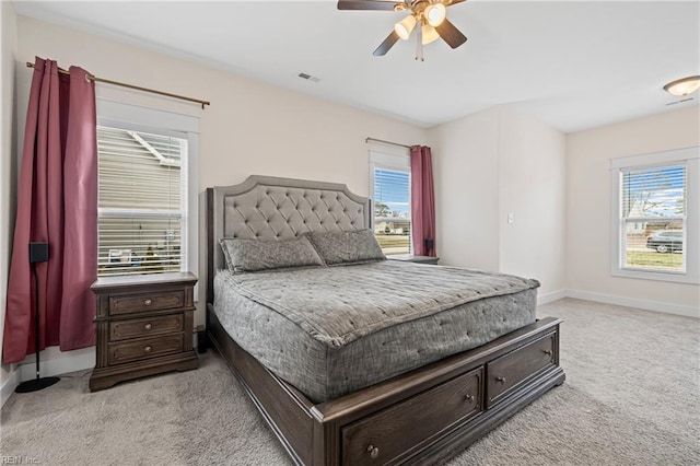 bedroom with ceiling fan, light colored carpet, visible vents, and baseboards