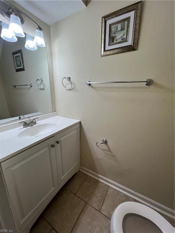 half bath with tile patterned floors, toilet, vanity, and a textured ceiling