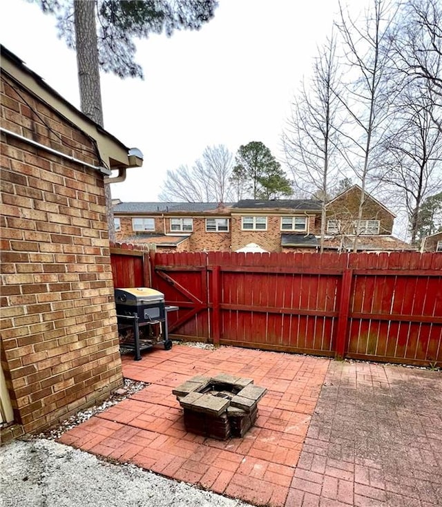 view of patio with area for grilling, fence, and a fire pit