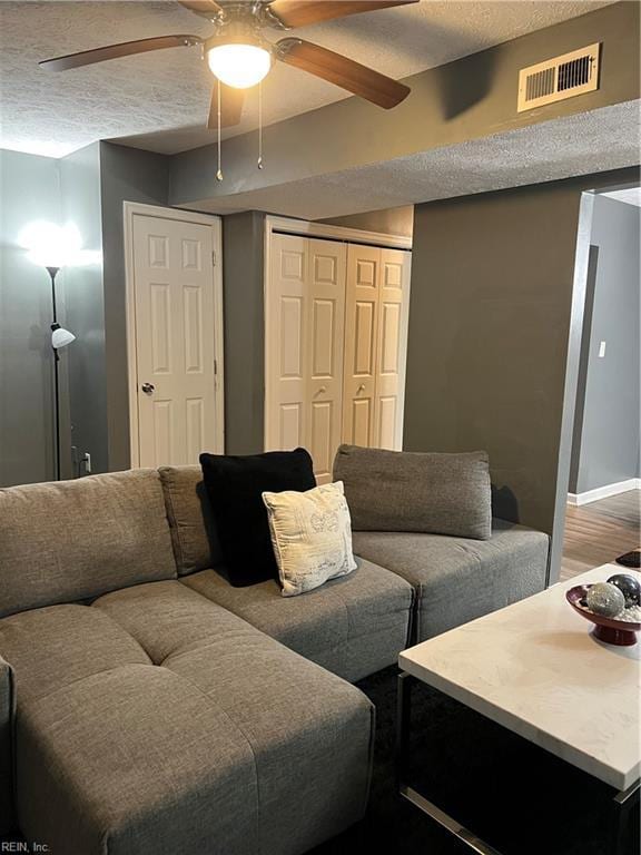 living room with visible vents, wood finished floors, a textured ceiling, and ceiling fan