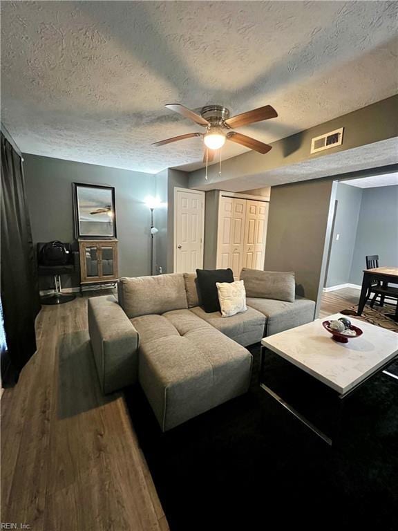 living area featuring a textured ceiling, wood finished floors, visible vents, and ceiling fan