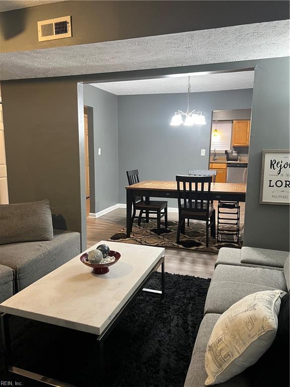 living area featuring visible vents, baseboards, wood finished floors, and a chandelier