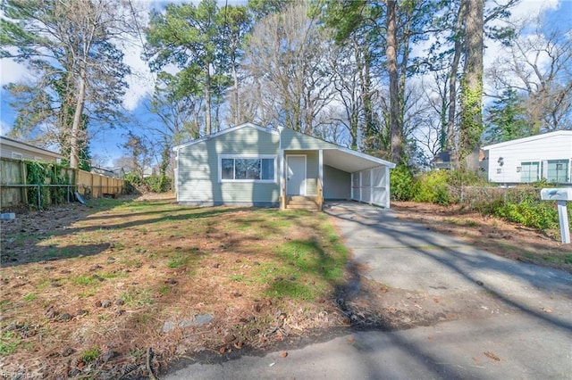 exterior space with a carport, concrete driveway, and fence