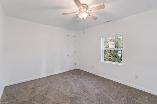 carpeted empty room with visible vents, baseboards, a textured ceiling, and ceiling fan