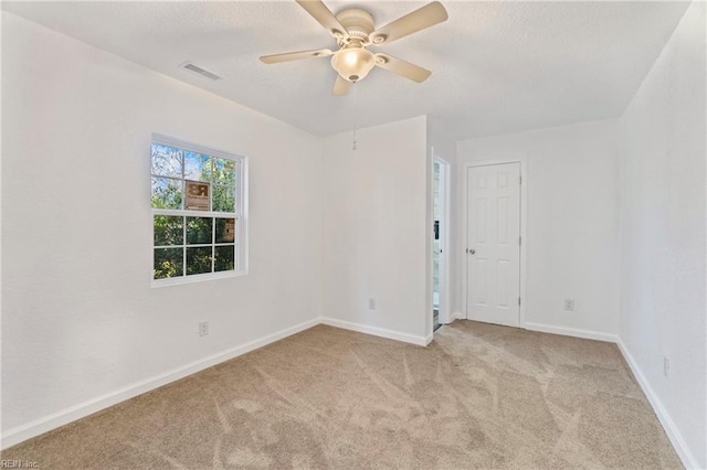 carpeted spare room with visible vents, baseboards, a textured ceiling, and ceiling fan