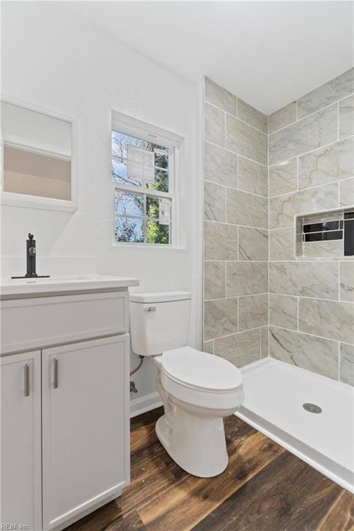 bathroom featuring vanity, toilet, wood finished floors, and a stall shower